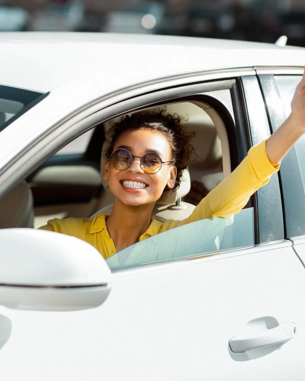 A driver leaning out of her car window, smiling and giving a thumbs up
