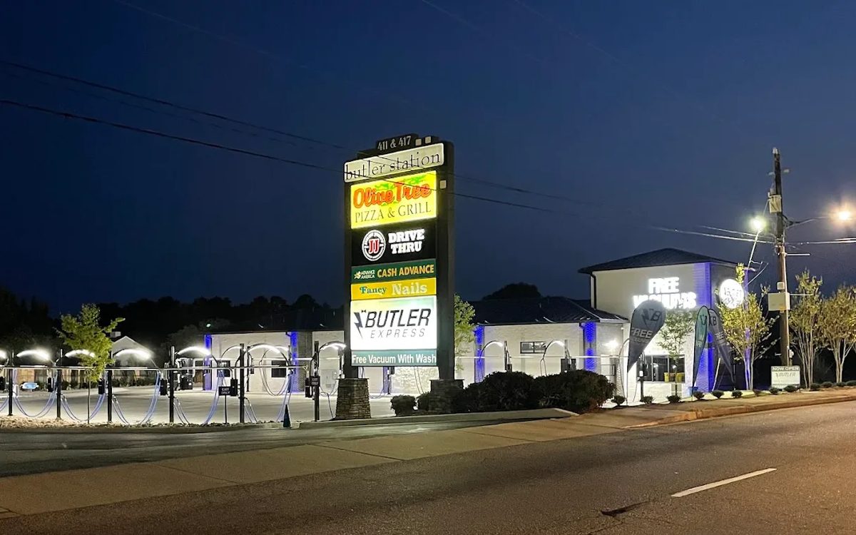 Butler Express Car Wash lit up after dark on W Butler Road, with the Butler Station sign out front and the vacuum bay lights on