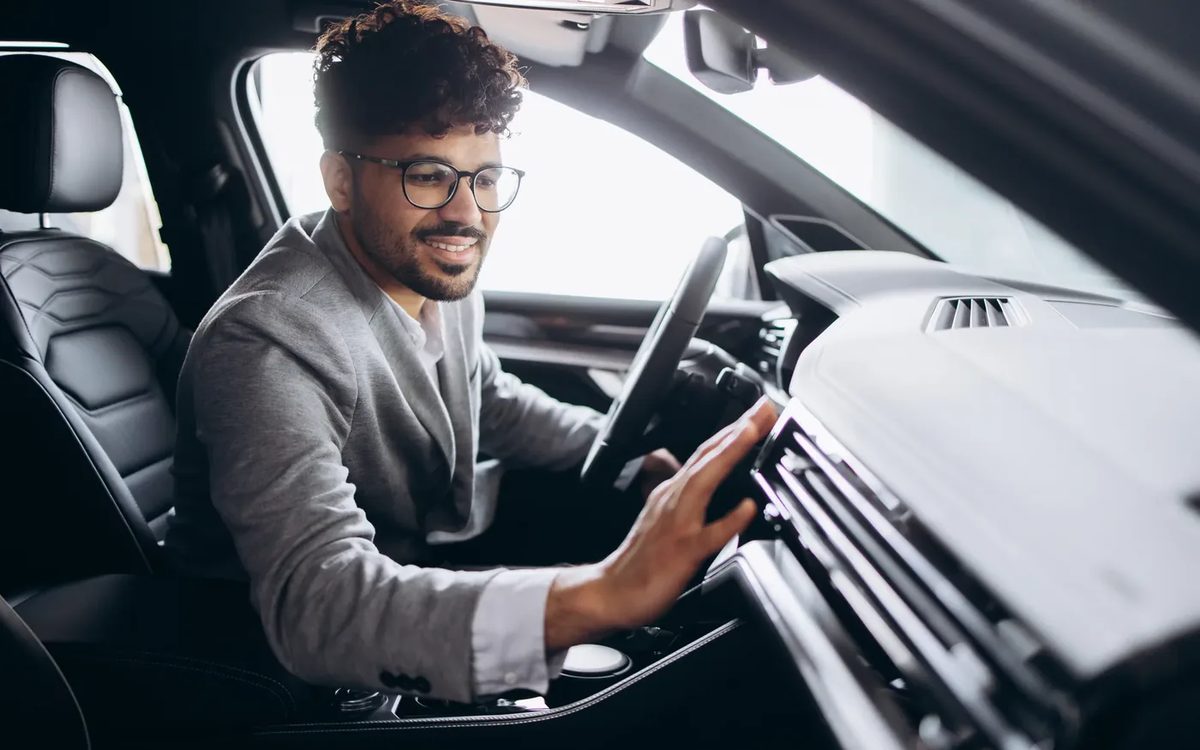A driver settling into a spotless car interior, hand on the dashboard controls