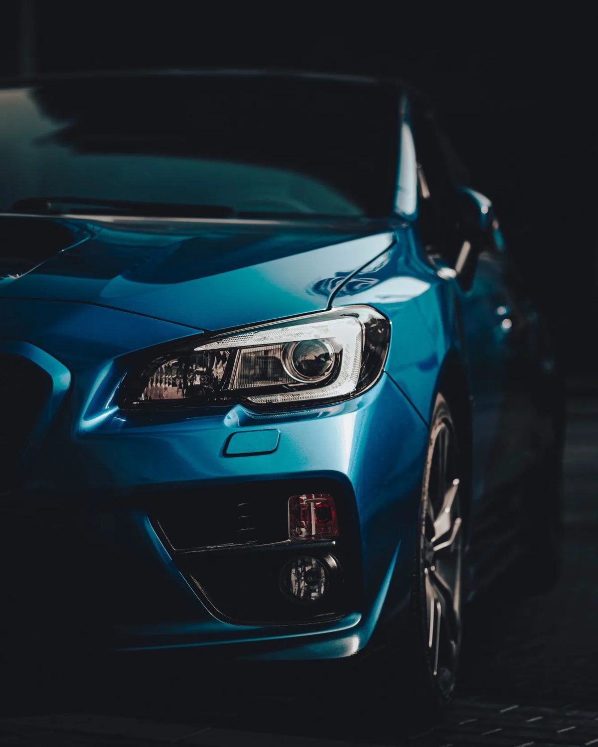 The front of a blue car picked out in low light